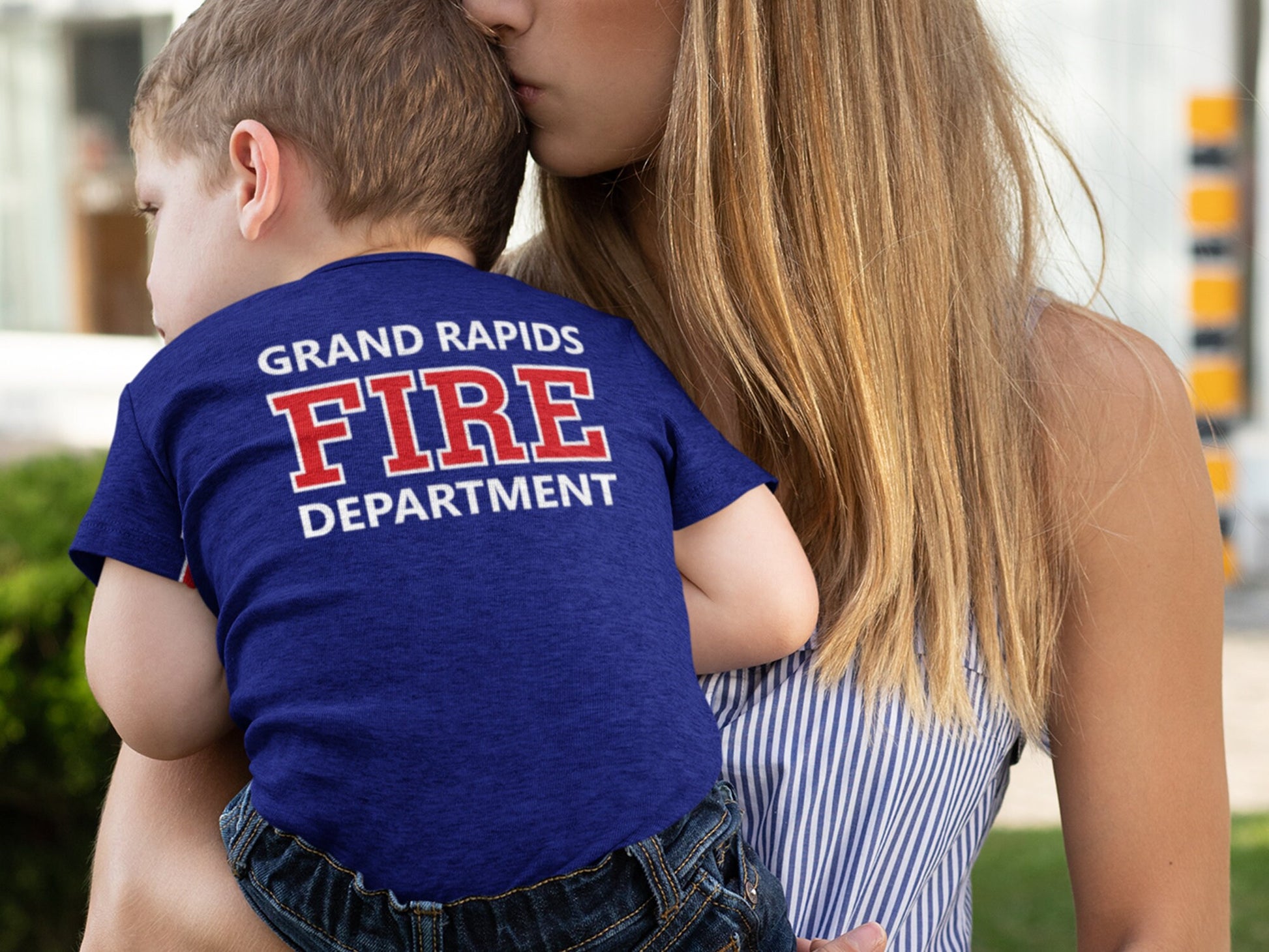 Close-up of the back of the toddler's bodysuit featuring the custom fire department name in red text on navy blue fabric
