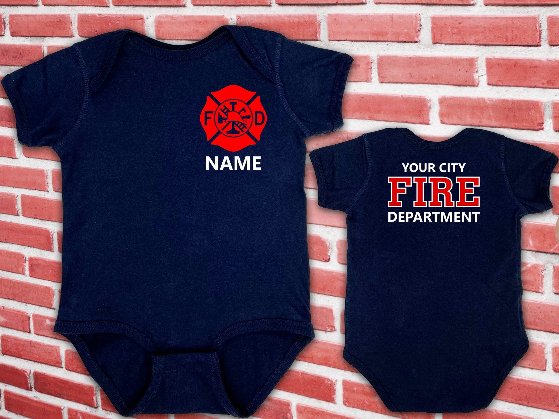 Navy blue baby bodysuit laid flat showing front design with red Maltese Cross and custom name; back displays personalized fire department text