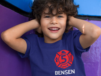Child wearing the personalized firefighter birthday t-shirt, showcasing the front design with the red Maltese Cross and custom details