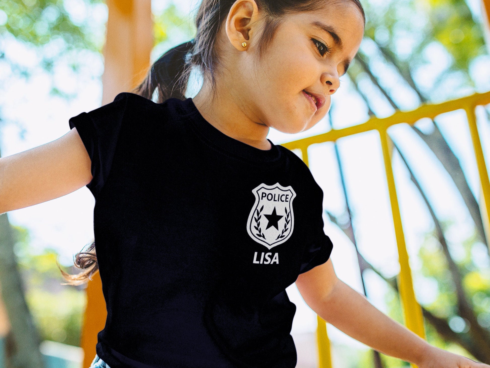 Young girl wearing a black t-shirt with a silver police badge design and the name 'LISA' printed below it.