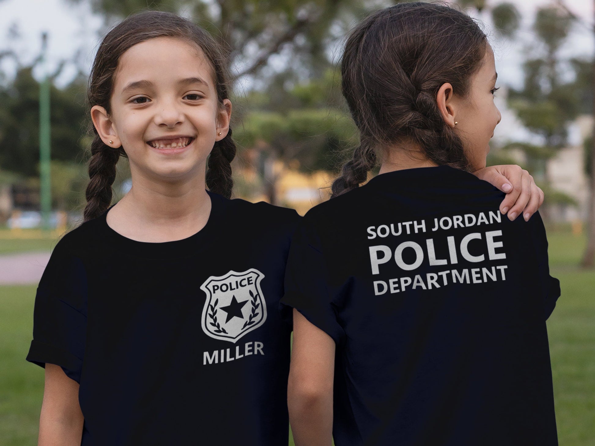 A black t-shirt with a silver police badge and the name 'MILLER' on the front. The back of the shirt has the text 'SOUTH JORDAN POLICE DEPARTMENT' in silver.