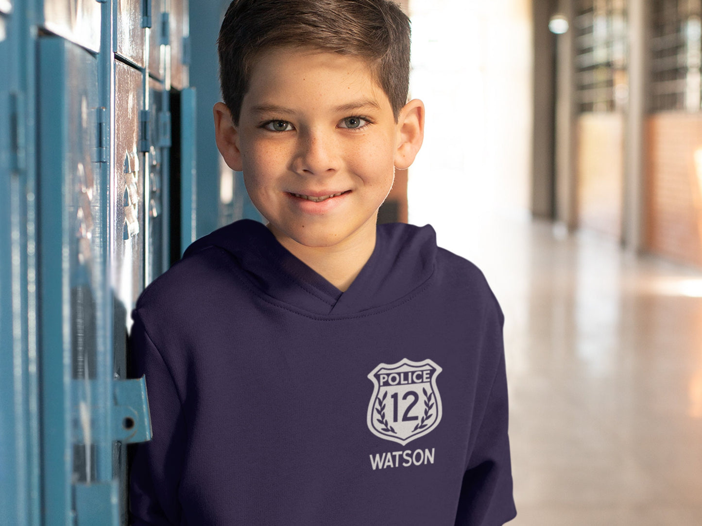 Child wearing the personalized police birthday hoodie, showcasing the front design with the white badge and custom details