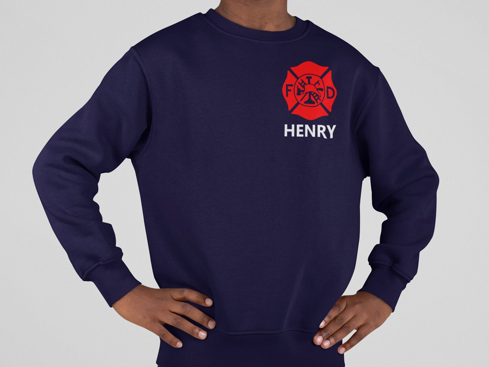 Youth wearing a navy blue sweatshirt with a red firefighter's Maltese cross logo and the text 'HENRY' underneath.