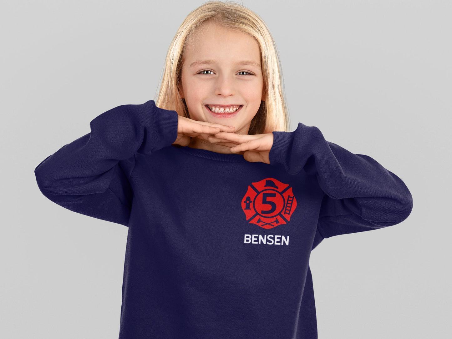 Girl wearing a navy blue sweatshirt with a red firefighter emblem featuring a number 5 and the text 'BENSEN'.