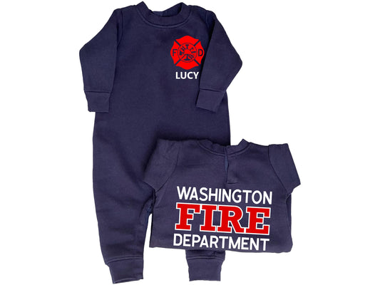 Navy blue long sleeve, long leg fleece bodysuit in baby sizes with custom red Maltese Cross on the front. The baby's name is under the Maltese Cross. A folded bodysuit shows the back side with a custom fire department name with "Fire" and "Department" underneath. The bodysuit has snaps at the back of the neck and up both legs.
