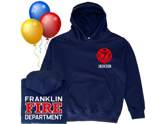 Navy blue hooded sweatshirt in youth sizes with custom red Maltese Cross on the front. Maltese Cross contains a custom number representing the youth's age. The youth's name is under the Maltese Cross. A folded hoodie shows a custom fire department name with "Fire" and "Department" written underneath. Three colorful balloons indicate a birthday theme.