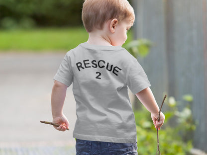 Back view of small boy holding sticks in each hand, wearing a gray short sleeve t-shirt that says "Rescue" and the number "2" as placeholders for custom text and age.