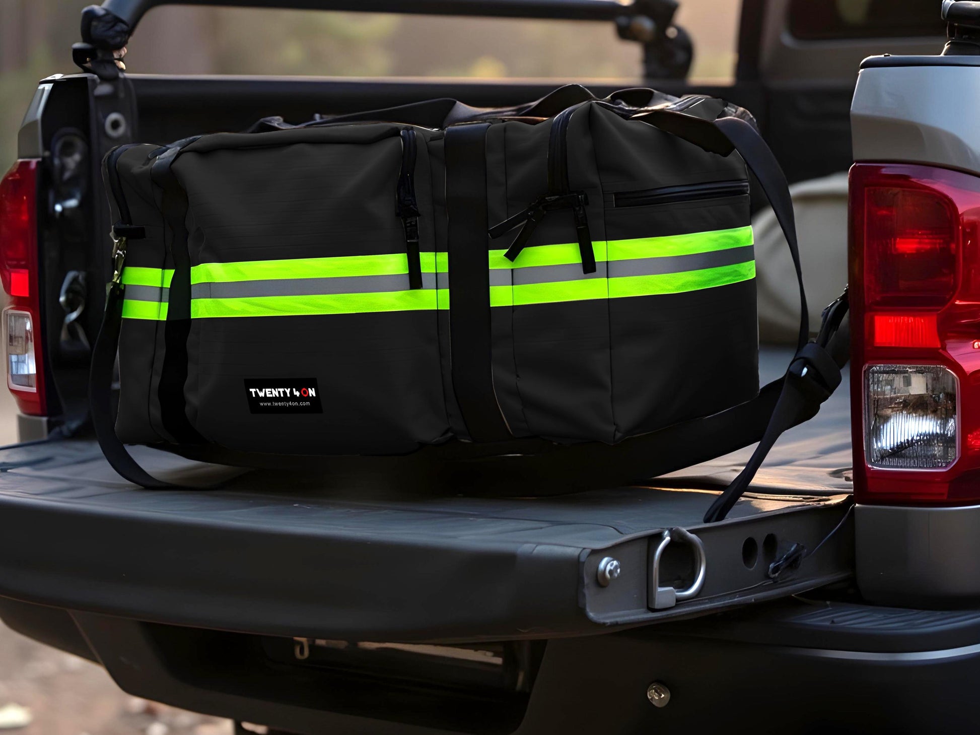Black firefighter bag with yellow reflective trim sitting in the bed of a pickup truck with the tailgate down.