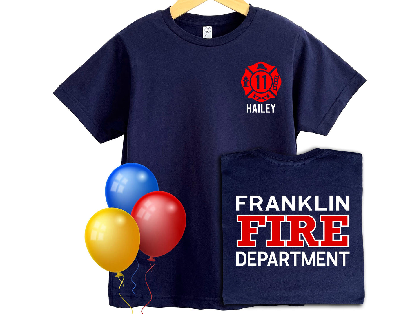 Navy blue kids’ t-shirt with a red firefighter Maltese cross on the front left chest, customizable with an age and name (shown as “11” and “Hailey”). The back of the shirt displays bold white and red text that can be personalized with any fire department name (shown as “FRANKLIN FIRE DEPARTMENT”). Three colorful balloons—yellow, red, and blue—add a festive touch. Perfect for birthdays or gifts for young firefighter fans.