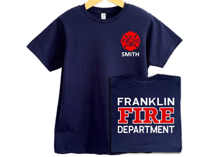 Navy blue youth sized firefighter T-shirt with red Maltese cross on left chest and personalized name underneath in white. Back of shirt features custom fire department in white and red text.