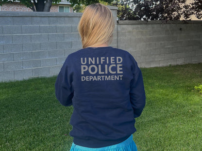 Back view of a girl wearing a navy blue sweatshirt with the text 'UNIFIED POLICE DEPARTMENT' printed on the back in silver.
