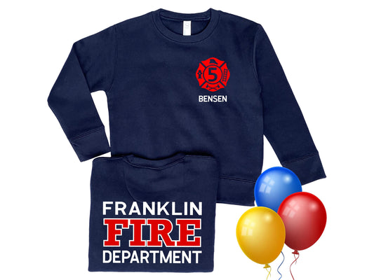 Navy long sleeve crew neck sweatshirt with red Maltese cross on left chest that contains the number 5 and the name Benson underneath in white text. The back of the birthday sweatshirt has red and white lettering, Franklin Fire Department. 3 bright balloons for birthday celebration.