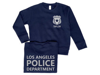 Navy blue crew neck sweatshirt with silver police badge on left chest and the name 'Taylor' underneath. Back of sweatshirt says 'Los Angeles Police Department' in silver text.